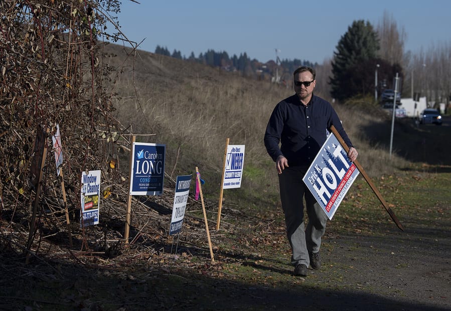 Eric Holt, who campaigned for Clark County Council chair, collects his signs after the election along Southeast Columbia Way in Vancouver on Thursday afternoon.