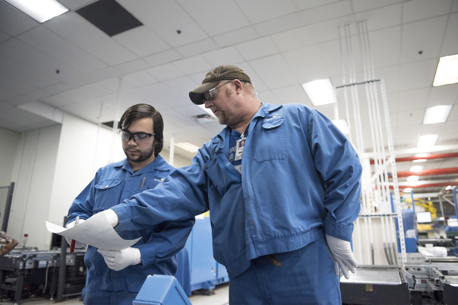 Nathaniel Salveta, left, takes direction from process technician Randall Chromey at Shin-Etsu Handotai (SEH) America on Wednesday afternoon. Salveta is enrolled in the Manufacturing Career Launch program, which will allow him to pursue a degree in mechatronics while working at SEH America.
