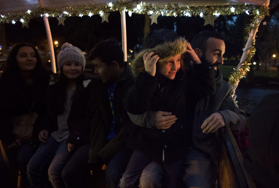 Ellie Russo of Redmond, Ore., 6, right, sits with her dad, Michael Russo of Vancouver, far right, as they ride on a horse-drawn carriage before the annual tree lighting ceremony Friday evening at Esther Short Park in Vancouver. Mill Creek Carriages gave rides around the park throughout the evening.
