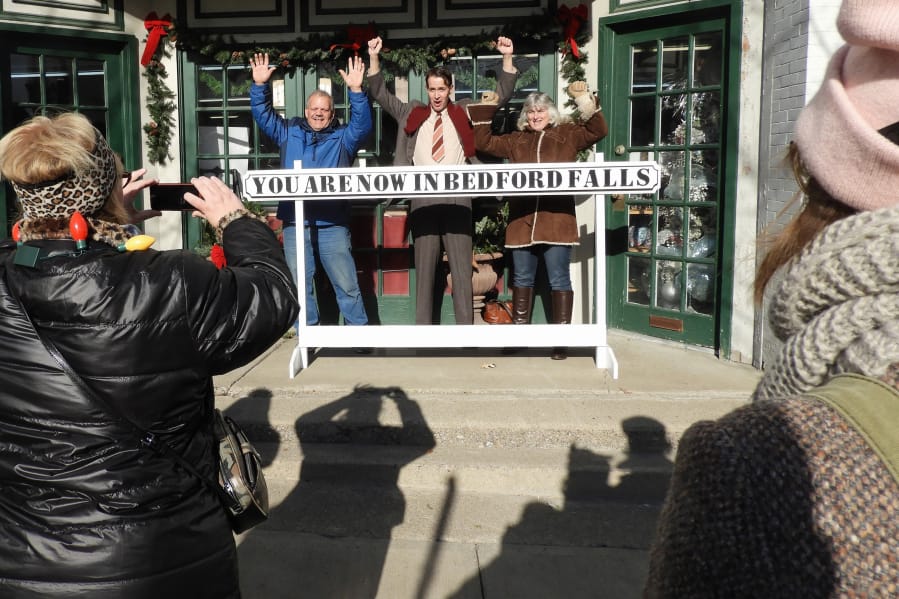 Joined by movie buffs, actor Brian Rohan, dressed as George Bailey, center, poses for photos during the It’s a Wonderful Life Festival in Seneca Falls, N.Y.