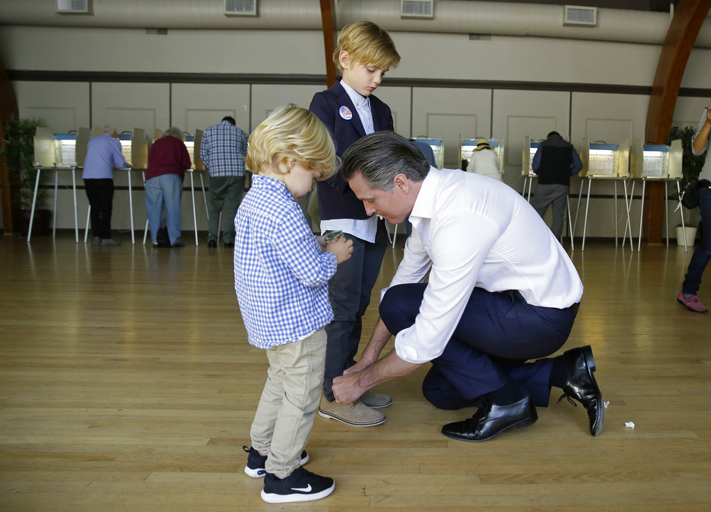 California gubernatorial Democratic candidate Gavin Newsom ties the shoe laces of his son Hunter, 7, as his son, Dutch, 2, looks on after voting Tuesday, Nov. 6, 2018, in Larkspur, Calif.