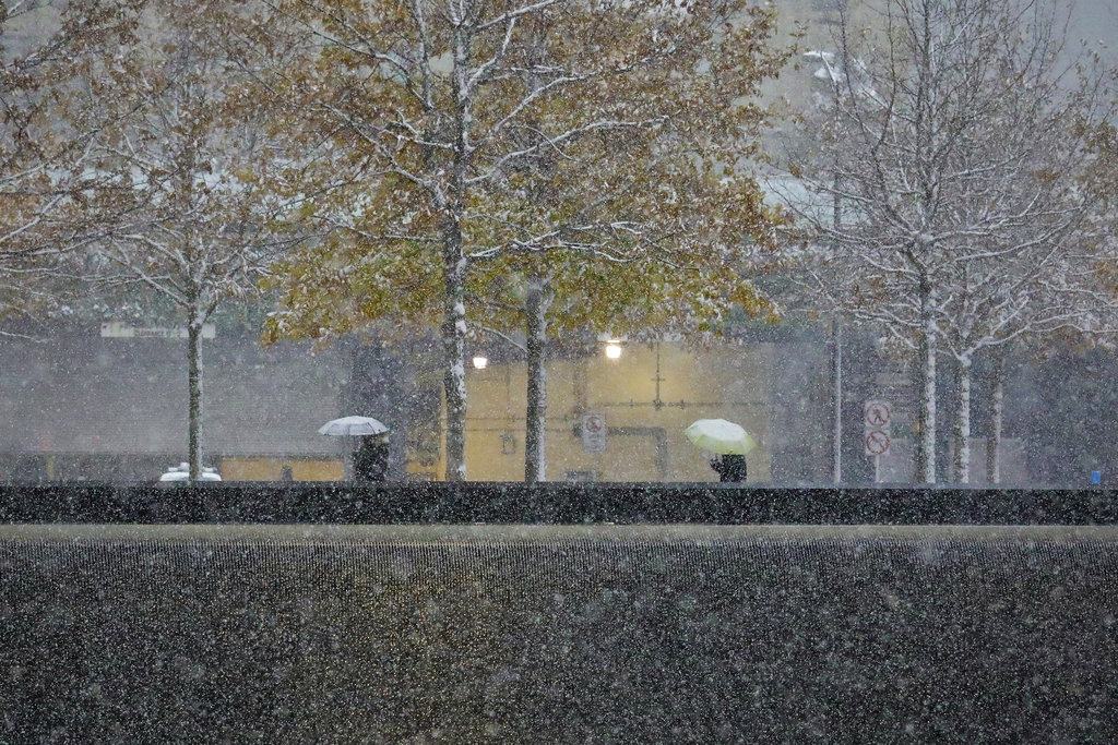 Visitors walk through the 9/11 Memorial in New York during a snowfall, Thursday Nov. 15, 2018. One of the first big storms of the season moved across the eastern half of the country Thursday, causing deadly traffic crashes and closing schools.