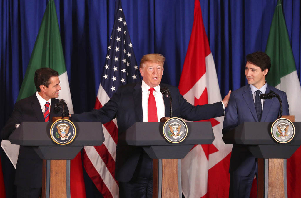 President Donald Trump, center, reaches out to Mexico's President Enrique Pena Nieto, left, and Canada's Prime Minister Justin Trudeau as they prepare to sign a new United States-Mexico-Canada Agreement that is replacing the NAFTA trade deal, during a ceremony at a hotel before the start of the G20 summit in Buenos Aires, Argentina, Friday, Nov. 30, 2018. The USMCA, as Trump refers to it, must still be approved by lawmakers in all three countries.