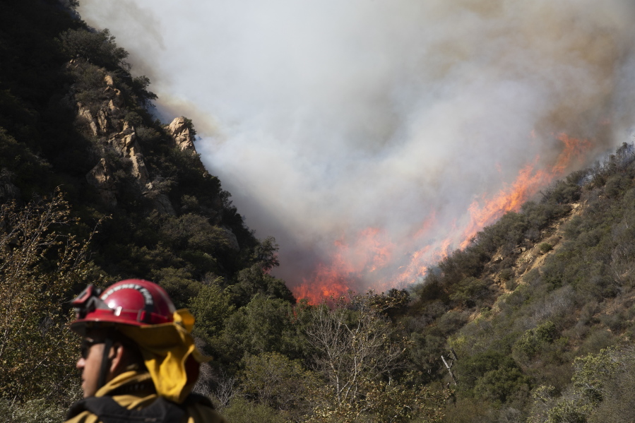 A firefighter monitors a wildfire burning along a hillside Sunday in Malibu, Calif. Jae C.