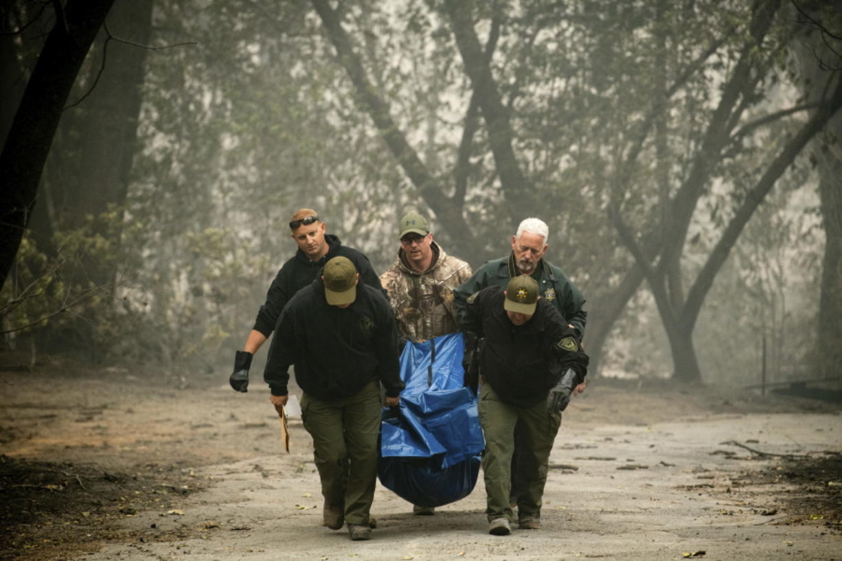 FILE - In this Nov. 10, 2018, file photo, sheriff's deputies recover the remains of a victim of the Camp Fire in Paradise, Calif. The massive wildfire that killed dozens of people and destroyed thousands of homes has been fully contained after burning for more than two weeks, authorities said Sunday, Nov. 25.