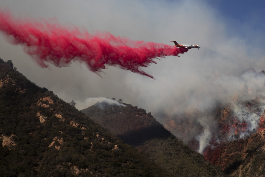 A plane drops fire retardant on a burning hillside Sunday, Nov. 11, 2018, in Malibu, Calif. (AP Photo/Jae C.