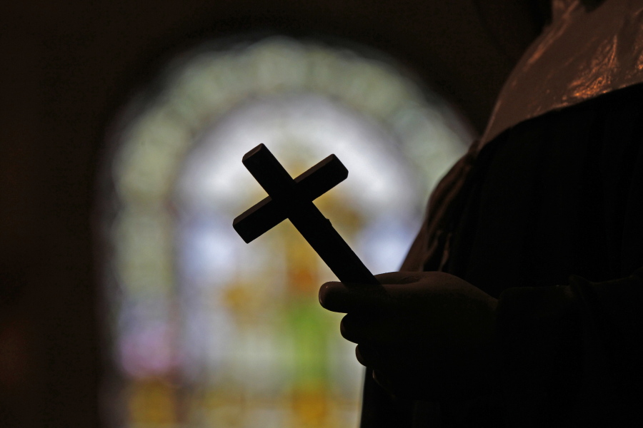This Dec. 1, 2012, file photo shows a silhouette of a crucifix and a stained glass window inside a Catholic Church in New Orleans. As U.S. Catholic bishops gather for an important national assembly, the clergy sex abuse crisis dominates their agenda.
