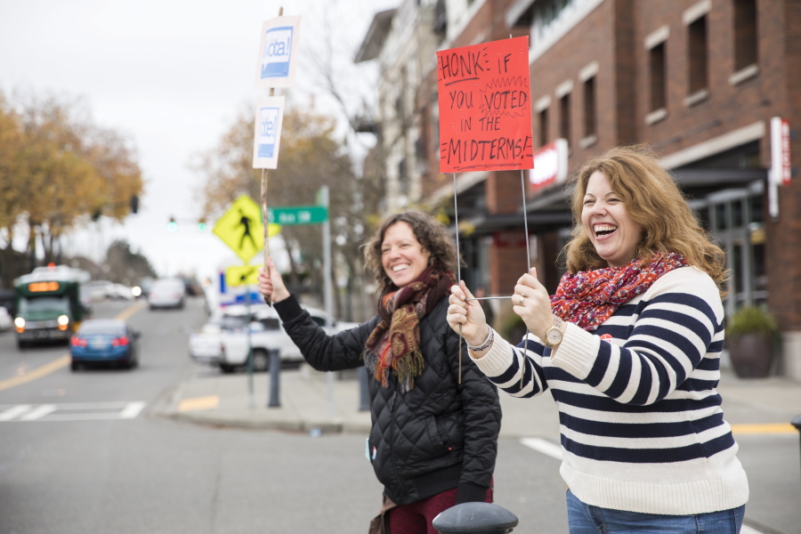 Tania Beaudet, left, and and M.J. McNeill hold signs encouraging people to vote in the midterms next to the King County Elections ballot drop box in Burien, Wash., Election Day, Tuesday, Nov. 6. 2018.