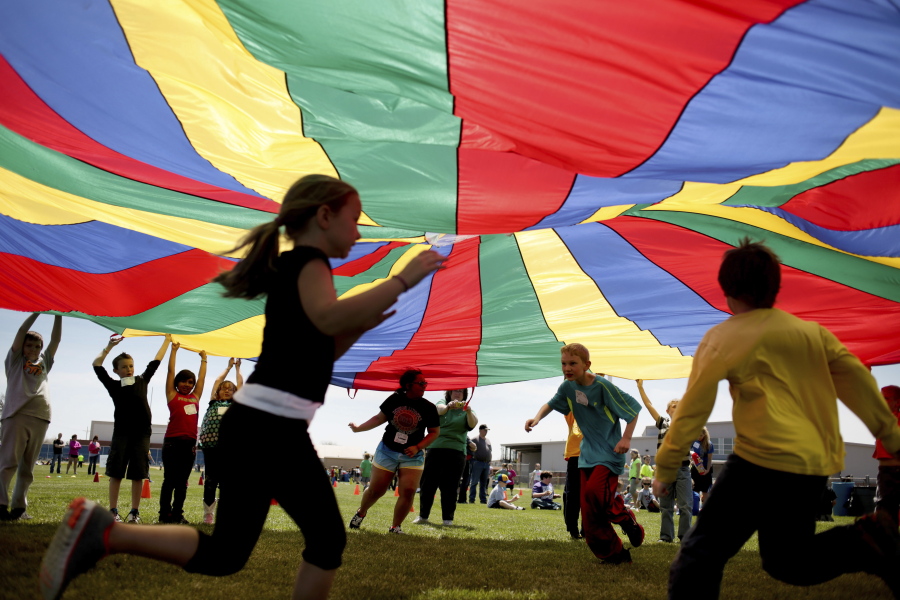 Elementary school third graders run under a rainbow colored tarp during the 15th Annual Kansas Kids Fitness Day, in Hutchinson, Kan. New federal guidelines released on Monday, Nov. 12, 2018, advise that children as young as age 3 should move more, sit less and get more active, and that any amount and any type of exercise helps health.