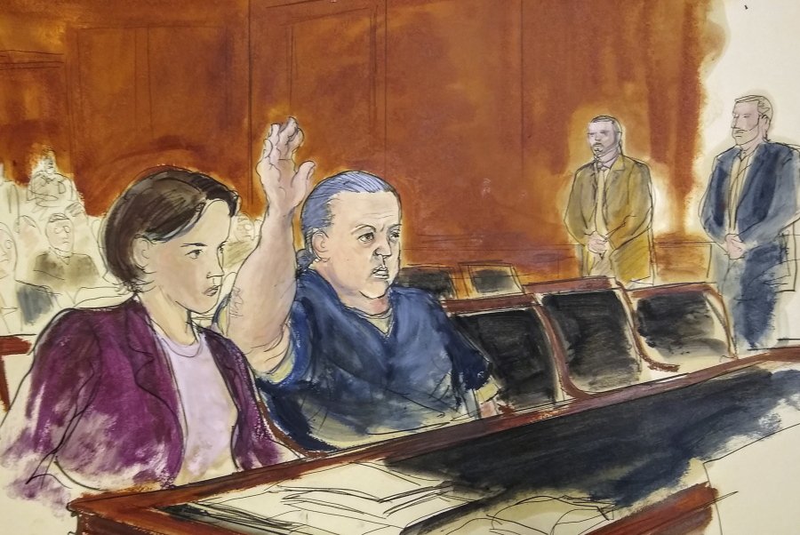 In this courtroom sketch, pipe bombs suspect Cesar Sayoc seated in court, raises his arm to swear to the truth of his statement of need for assigned counsel, during his presentment in Manhattan Federal Court Tuesday, Nov. 6, 2018, in New York. Sayoc, who faces charges for allegedly mailing more than a dozen explosive devices to prominent Democrats, CNN and critics of Republican President Donald Trump, has been ordered held without bail in New York. At left is Federal Defender Sarah Baumgartel, while standing far right are U.S. marshals.
