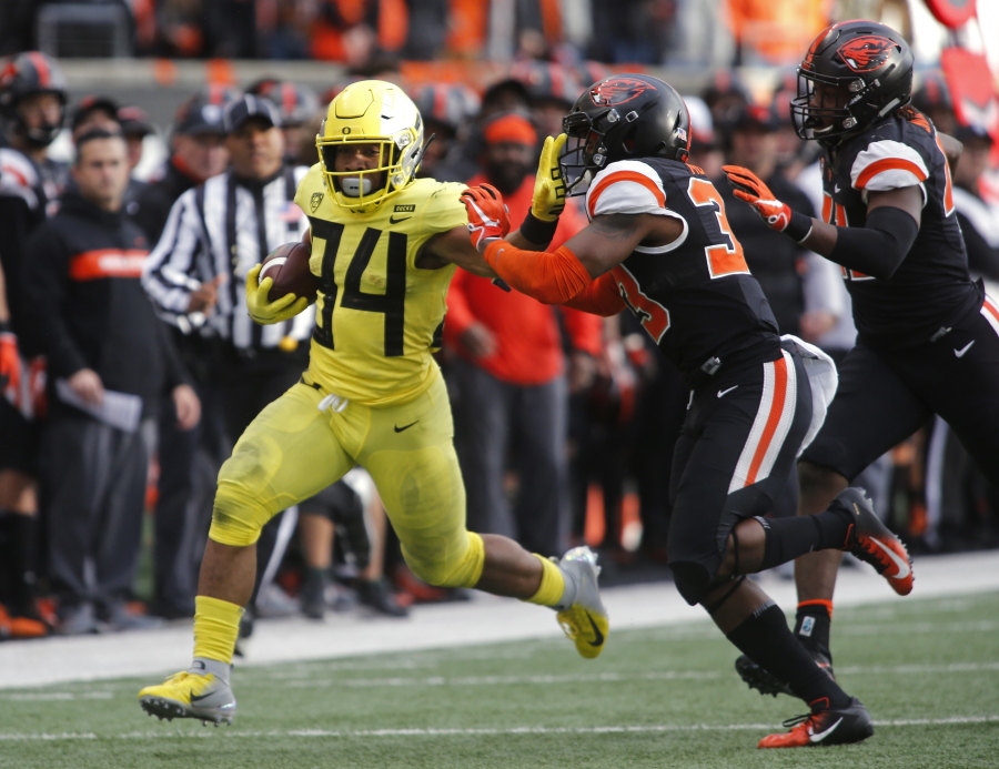 Oregon running back C.J. Verdell (34) tries to stiff-arm Oregon State safety Jalen Moore (33) on a run during the second half of an NCAA college football game in Corvallis, Ore., Friday, Nov. 23, 2018. Oregon won 55-15. (AP Photo/Timothy J.