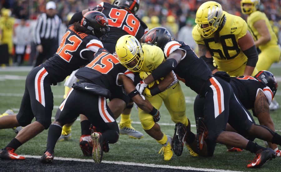 Oregon running back C.J. Verdell, center, bulls his way past Oregon State’s Doug Taumoelau (42), Jeffrey Manning Jr. (15) and Hamilcar Rashed Jr (right) for a touchdown in the first half of an NCAA football game in Corvallis, Ore., on Friday, Nov. 23, 2018. (AP Photo/Timothy J.