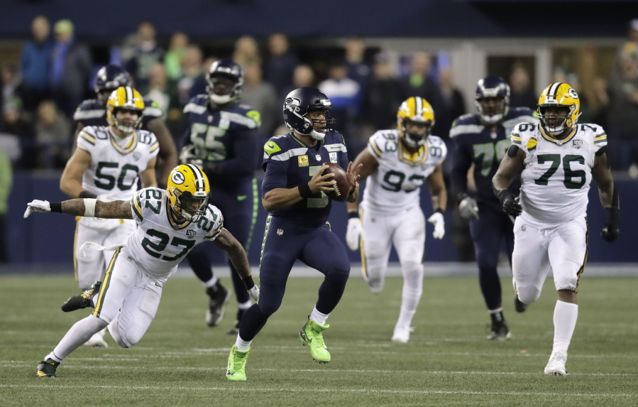 Seattle Seahawks quarterback Russell Wilson (3) scrambles away from Green Bay Packers defensive back Josh Jones (27) during the first half of an NFL football game Thursday, Nov. 15, 2018, in Seattle.