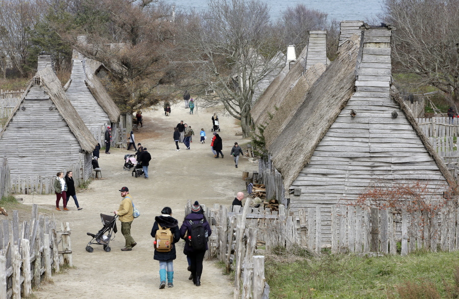 In this Sunday, Nov. 18, 2018, photo, visitors to Plimoth Plantation, a living history museum village where visitors can get a glimpse into the world of the 1627 Pilgrim village, walk among buildings, in Plymouth, Mass. Plymouth, where the Pilgrims came ashore in 1620, is gearing up for a 400th birthday, and everyone's invited, especially the native people whose ancestors wound up losing their land and their lives.