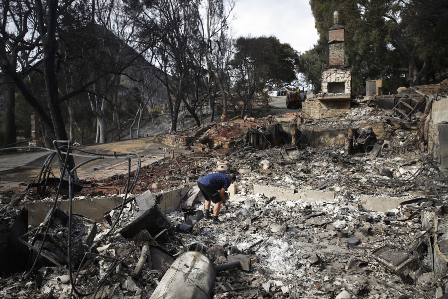 Roger Kelton searches through the remains of his mother-in-law’s home leveled by the Woolsey Fire on Tuesday in the southern California city of Agoura Hills. (AP Photo/Jae C.