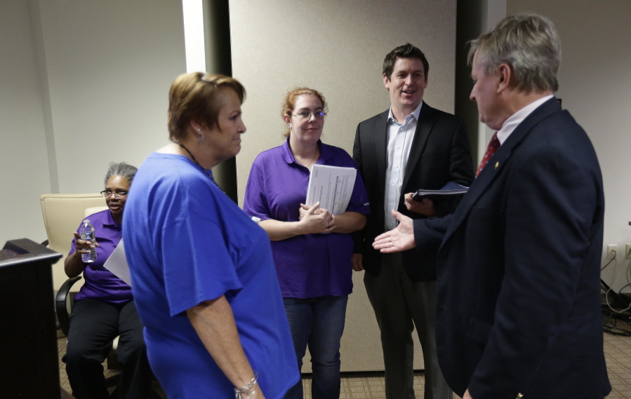 In this Aug. 23, 2018, photo Jim Baker, second from right, a campaigner at the Private Equity Stakeholder Project and former Toys R Us employees Ann Marie Reinhart, left, and Wendy Kaltenbach speak with North Carolina State Treasurer Dale Folwell, right, following public comments portion of an investment advisory committee meeting of the North Carolina Department of State Treasure in Raleigh, N.C. Two private equity owners of Toys R Us announced Tuesday, Nov. 20, that they will be handing over a $20 million hardship fund to the thousands of former workers left jobless and without severance after the chain liquidated in June.