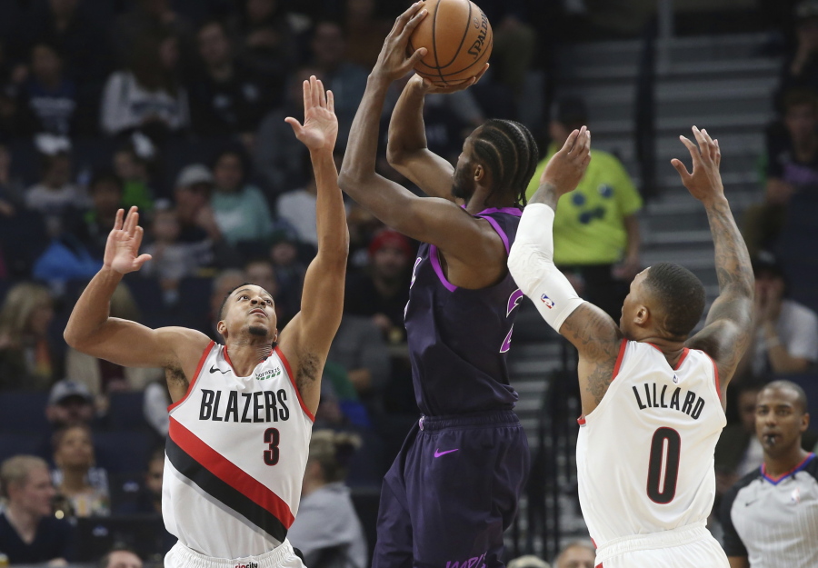 Portland Trail Blazers’ CJ McCollum, left, and Damian Lillard, right, defend as Minnesota Timberwolves’ Karl-Anthony Towns shoots during the first half of an NBA basketball game Friday, Nov. 16, 2018, in Minneapolis.