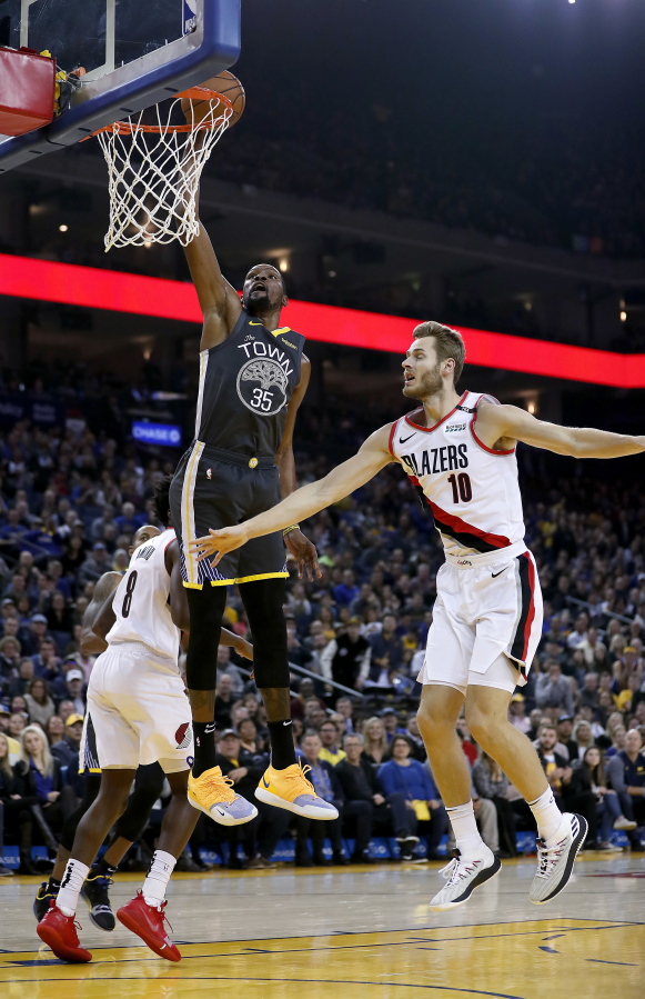Golden State Warriors forward Kevin Durant (35) dunks in front of Portland Trail Blazers forward Jake Layman (10) during the first half of an NBA basketball game in Oakland, Calif., Friday, Nov. 23, 2018.