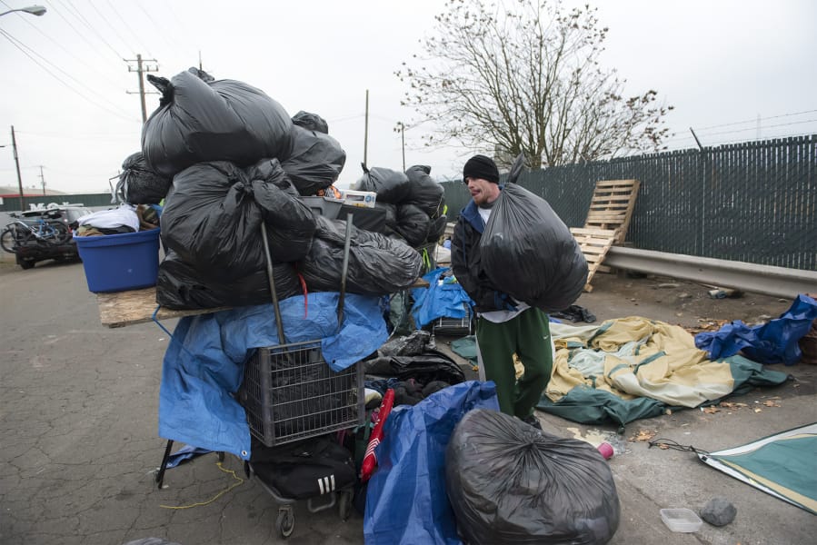 William Burke collects his belongings in black trash bags Nov. 21 while moving off his camping spot near Share House in downtown Vancouver.