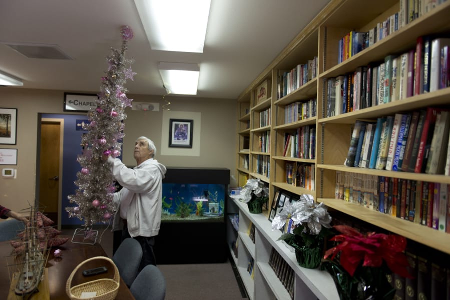 Anthony Moreno, a volunteer, installs a Christmas tree inside the library at the Fort Vancouver Seafarers Center. The center held its annual Christmas party Sunday, with about 50 people in attendance.