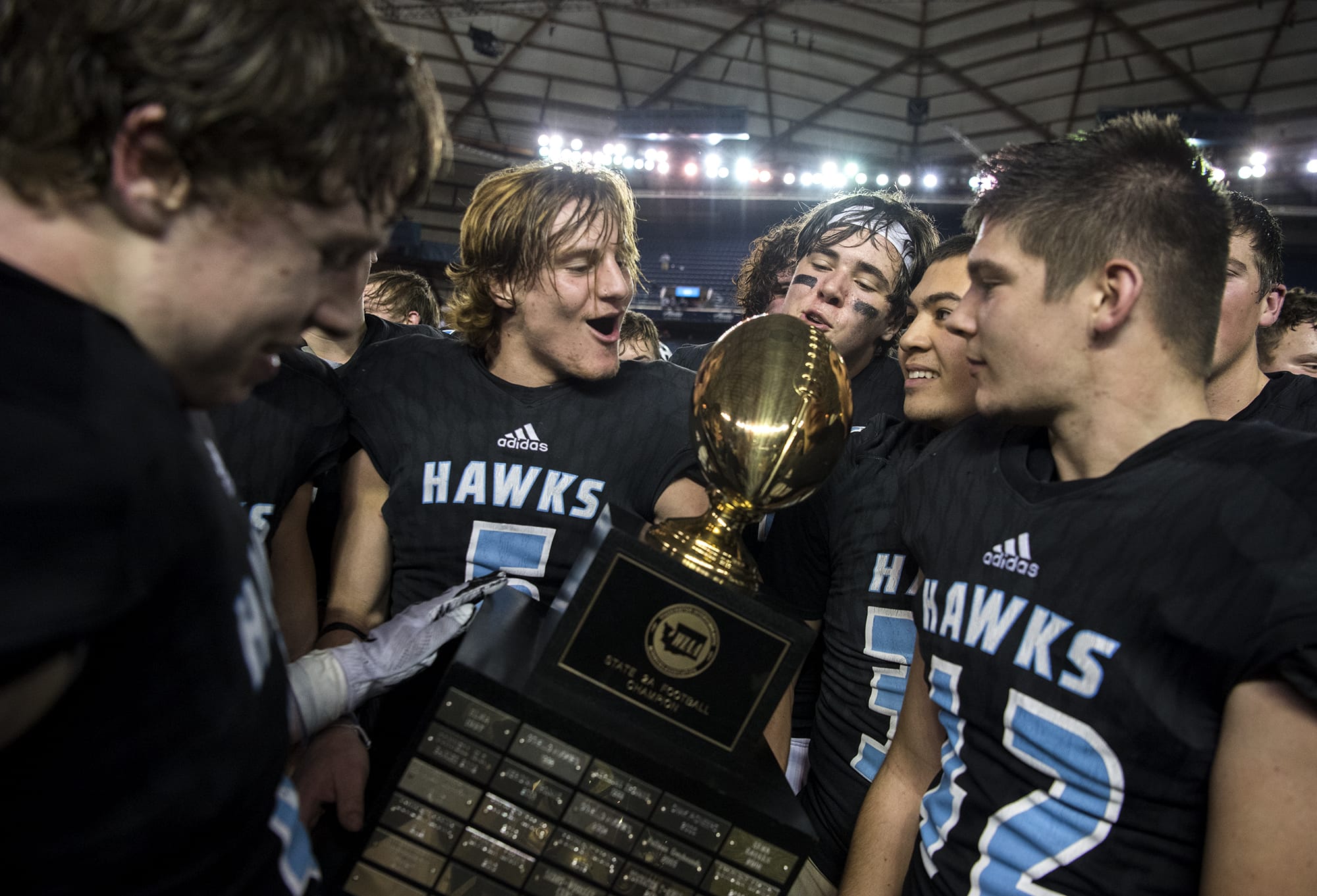 Hockinson's Wyatt Jones (5) holds the 2A state football championship game trophy as the team celebrates their win on Saturday, Dec. 1, 2018, in Tacoma, Wash. Hockinson defeated Lynden 42-37.