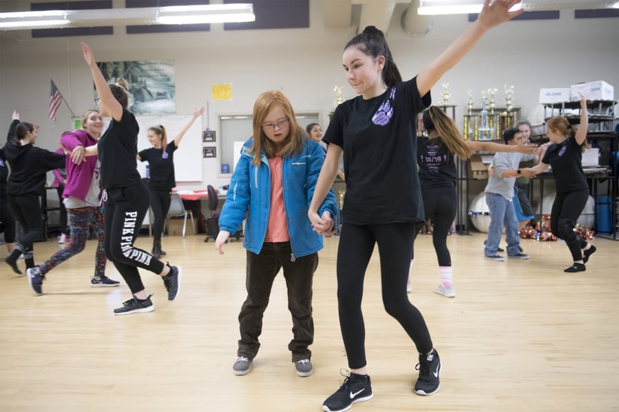 Hannah Roberts, left, is led through the steps of a dance performance by 14-year-old Victoria Self during a rehearsal at Heritage High School.