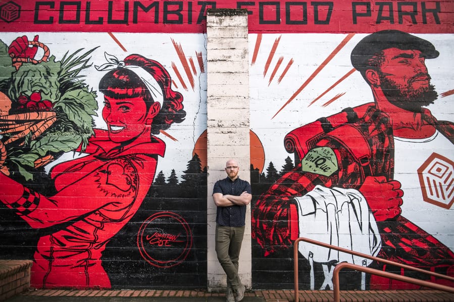 Alex Mickle, founder of the Columbia Food Park, stands in front of a new mural that adorns the eastern wall of the Columbia Food Park, painted by Portland artist Jonathan Case.