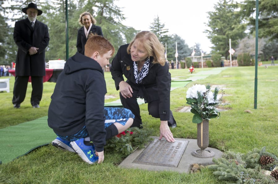Vancouver Mayor Anne McEnerny-Ogle and Aiden Shields, place a wreath on the grave of Andrew Shields, at the National Wreaths Across America Day in Vancouver Saturday. Andrew Shields was a Battle Ground resident and combat medic killed in Afghanistan in 2008.