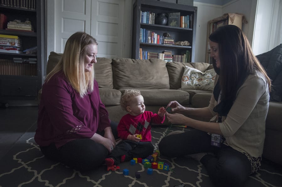 Nurse Elise Stills, right, tries to see if James, the 17-month-old son of Randell Farnham, will try to stack blocks, a sign of developmental progress. Stills has been a familiar presence in Farnham’s home as part of a county program that provides home visits to low-income, first-time mothers.