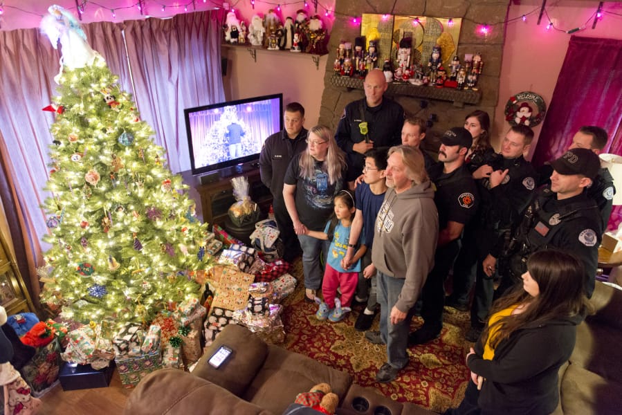 Vancouver police officers and firefighters pose for snapshots Sunday after delivering presents to the Pierro family, whose 6-year old daughter, Kierra, nearly died when she collapsed with cardiac arrest the weekend before Thanksgiving.