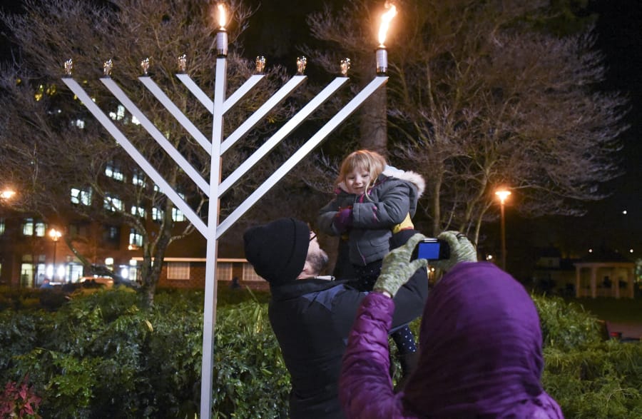 Ephraim Barstad holds up his daughter, Selah Barstad, 3, for a photo at the annual menorah lighting at Esther Short Park in 2017. The Chabad Jewish Center has held a public Hanukkah celebration in the park since 2004.