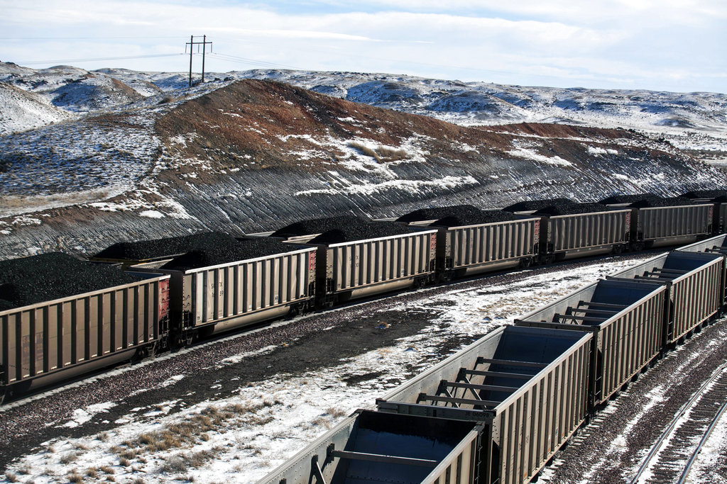 FILE - In this Jan. 9, 2014, file photo, rail cars are filled with coal and sprayed with a topper agent to suppress dust at Cloud Peak Energy's Antelope Mine north of Douglas, Wyo. Four states with climate change worries are asking a judge to stop the Trump administration from selling coal from public lands. Attorneys general from California, New Mexico, New York and Washington are due in a U.S. courtroom in Montana on Thursday, Dec. 13, 2018, to argue the sales put the climate at risk and shortchange taxpayers.