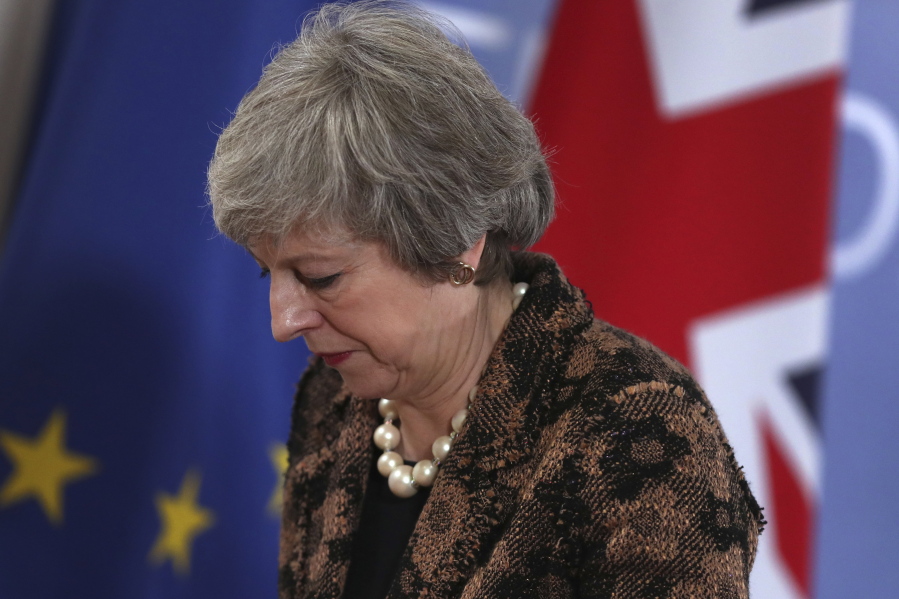British Prime Minister Theresa May walks by the Union flag and the EU flag as she departs a media conference at an EU summit in Brussels, Friday, Dec. 14, 2018. European Union leaders expressed deep doubts Friday that British Prime Minister Theresa May can live up to her side of their Brexit agreement and they vowed to step up preparations for a potentially-catastrophic no-deal scenario.