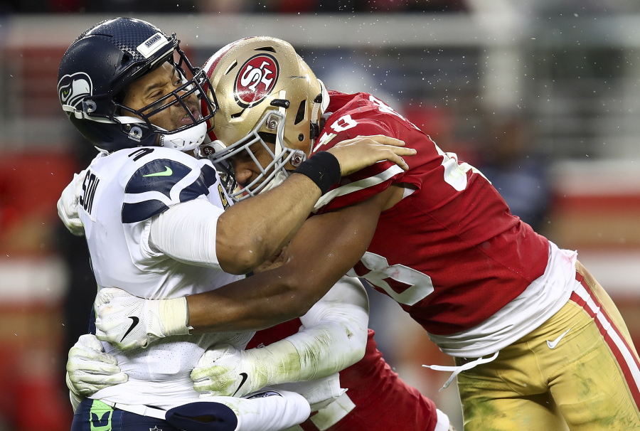Seattle Seahawks quarterback Russell Wilson, left, is hit after passing by San Francisco 49ers linebacker Fred Warner, right, and linebacker Elijah Lee, bottom, during the second half of an NFL football game in Santa Clara, Calif., Sunday, Dec. 16, 2018.