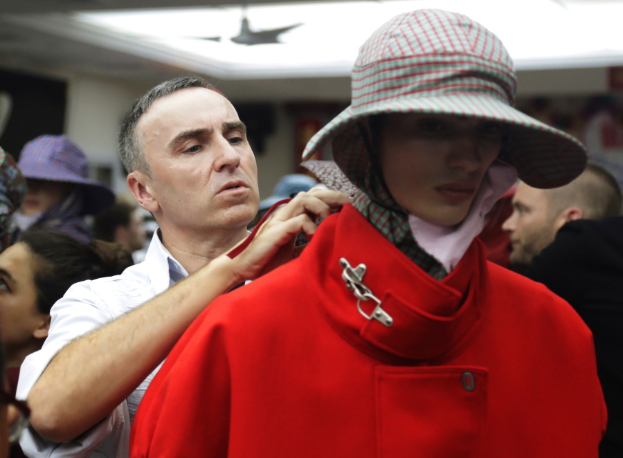 FILE - In this Tuesday, July 11, 2017 file photo, Fashion designer Raf Simons, left, makes adjustments before his fashion show during Men’s Fashion Week in New York. Designer Raf Simons is parting ways with Calvin Klein after two years with the fashion company. Calvin Klein announced in a statement Friday, Dec. 21, 2018 the Belgian designer’s departure as the chief creative officer was amicable. The company said it decided on a new brand direction different from Simons’ creative vision.