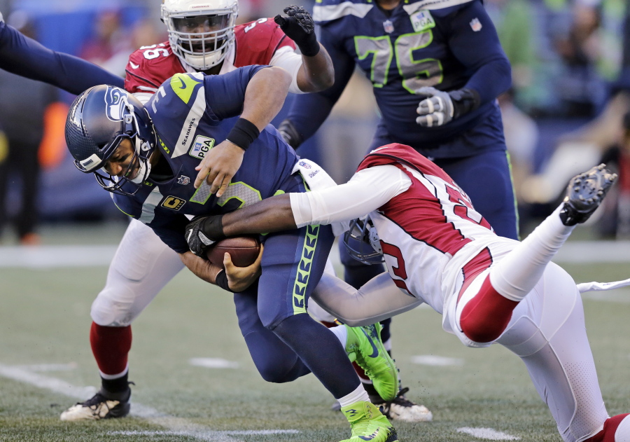 Seattle Seahawks quarterback Russell Wilson, left, is sacked by Arizona Cardinals’ Chandler Jones, right, during the first half of an NFL football game, Sunday, Dec. 30, 2018, in Seattle.