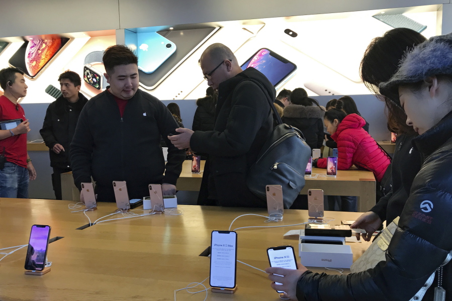 People buy latest iPhone while others try out its latest model at an Apple Store in Beijing on Tuesday. China’s economy czar and the U.S. Treasury secretary discussed plans for talks on a tariff battle, the government said Tuesday, indicating negotiations are going ahead despite tension over the arrest of a Chinese tech executive.