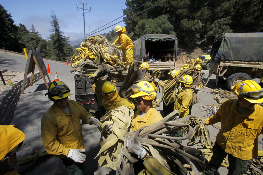FILE - In this Aug. 6, 2016 file photo, members of the California National Guard help load about 5 miles of used wildland fire hose in Palo Colorado Canyon, south of Monterey Calif., during efforts to fight the Soberanes Fire. When a fire burned across Big Sur two years ago and threatened hundreds of homes scattered on the scenic hills, firefighters responded with overwhelming force, attacking flames from the air and ground. The so-called Soberanes Fire burned its way into the record books as the most expensive wildland firefight in U.S. history in what a new report calls “an extreme example of excessive, unaccountable, budget-busting suppression spending that is causing a fiscal crisis in the U.S.
