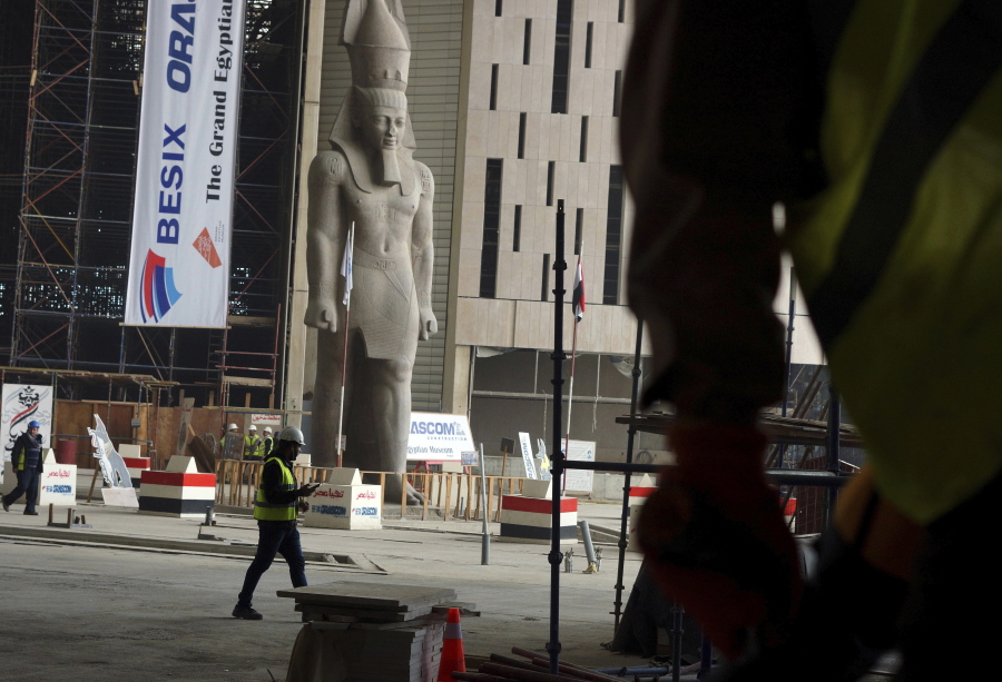 In this Sunday, Dec. 16, 2018 photo, work continues in the shadow of a statue of Pharaoh Ramses II, at the Grand Egyptian Museum, under construction in Giza, Egypt. Thousands of Egyptians are laboring in the shadow of the pyramids to erect a monument worthy of the pharaohs. The Grand Egyptian Museum has been under construction for well over a decade and is intended to show off Egypt’s ancient treasures while attracting tourists to help fund its future development.