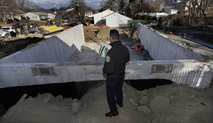 Lawrence, Mass. police officer Ivan Soto looks as contractors work on a new foundation at the former site of his family home, which was destroyed on Sept. 13, 2018 after a gas line explosion in Lawrence, Mass., on Friday. Following a gas line failure, which displaced thousands of Lawrence residents, many residents and business owners are dealing with the after effects of the crisis. Officials announced that most have been connected back to their service following the fires, explosions and loss of their main heating utility, but there are many issues which still need to be solved.