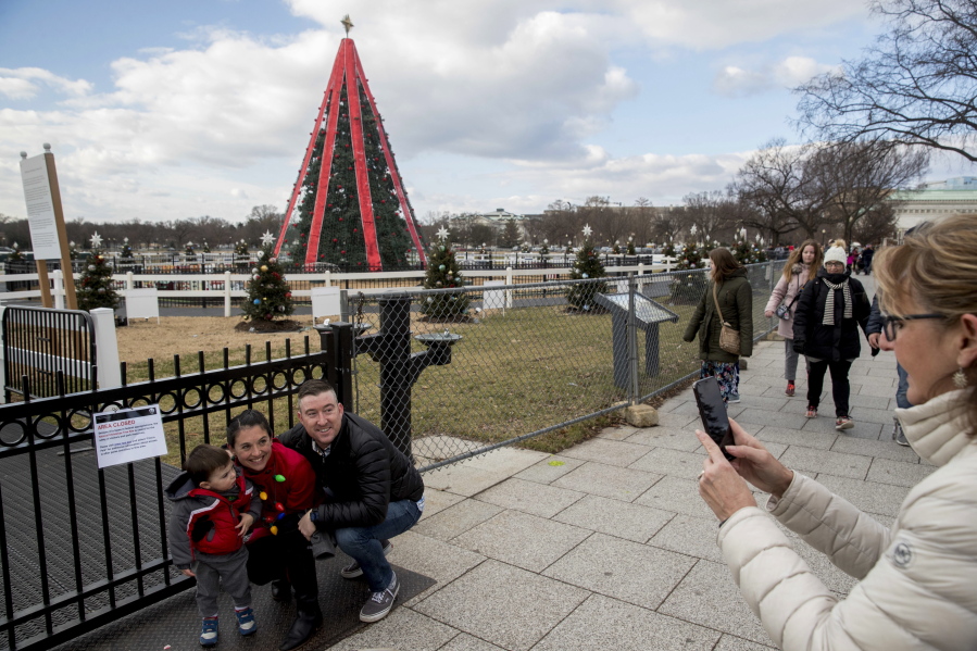 Casie Tavares-Stoeckel, her husband, Luke Tavares-Stoeckel, and their 1-year-old son, Luke, pose Monday for Casie’s mother, Cathy Tavares of Farmville, Md., right, in front of a closed sign as they are turned away from their yearly tradition of visiting the National Christmas Tree on the Ellipse near the White House in Washington.