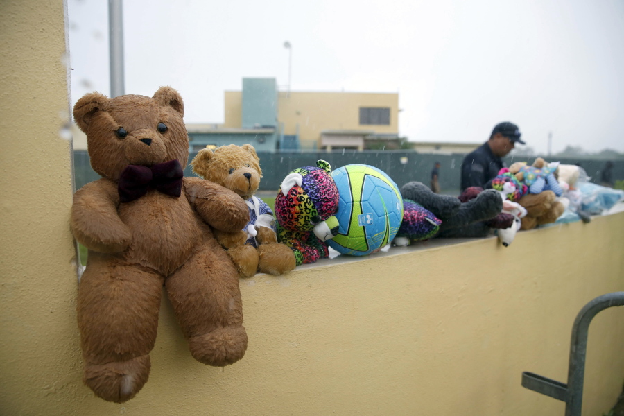 A guard walks past toys placed for migrant children by protesters as they marched in June to the Homestead Temporary Shelter for Unaccompanied Children in Homestead, Fla.