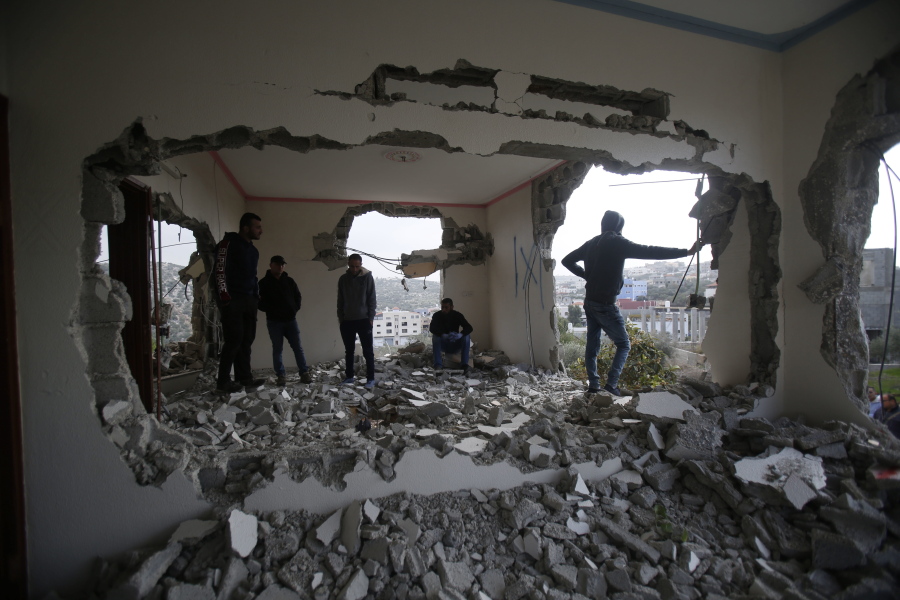 Palestinians examine a house after it was partially demolished by the Israeli army in the village of Shweikeh, near the West Bank city of Tulkarem, Monday, Dec. 17, 2018. The Israeli military has partially demolished the home of Ashraf Naalweh, a Palestinian accused of killing two Israelis in a West Bank attack two months ago.