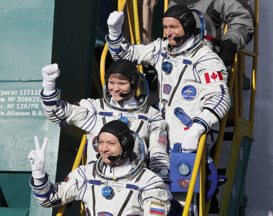 Russian cosmonaut Oleg Kononenko, from front, U.S. astronaut Anne McClain and Canadian astronaut David Saint Jacques, crew members of the mission to the International Space Station, wave before the launch of Soyuz-FG rocket.