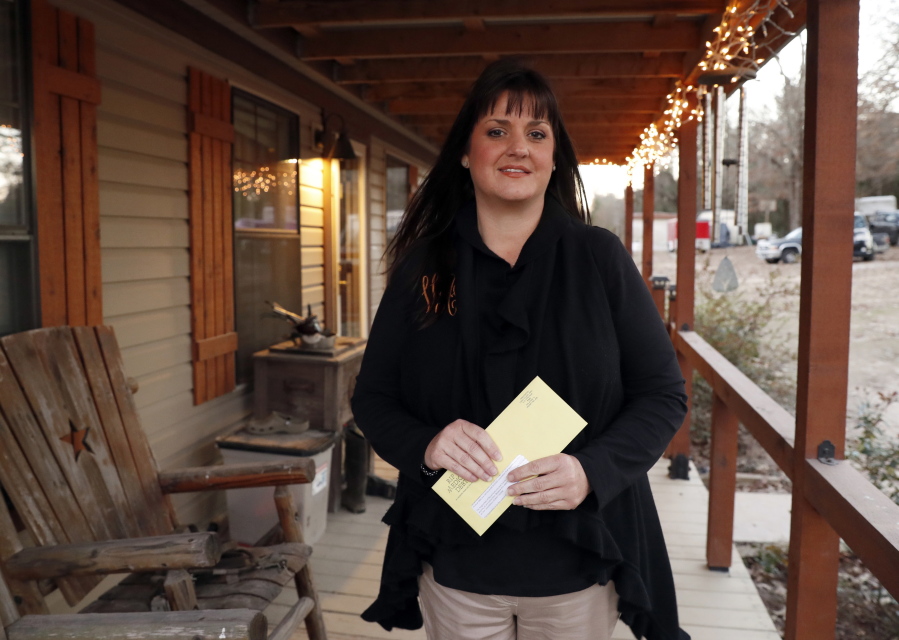Reagen Adair holds on to a RIP Medical Debt yellow envelope as she poses for a photo at her home in Murchison, Texas. The co-founders of RIP Medical Debt buy millions of dollars in past-due medical debt for pennies on the dollar. But instead of hounding people to pay, they send letters saying the debt is erased, no strings attached.