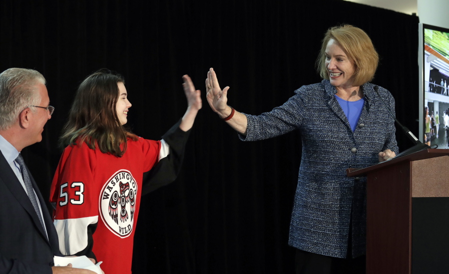 Seattle Mayor Jenny Durkan, right, high-five’s Washington Wild hockey team wing Jaina Goscinski, 11, as Tod Leiweke, CEO of NHL Seattle, looks on during a news conference Oct. 2 in Seattle. The NHL Board of Governors is meeting Tuesday in Sea Island, Ga., to give final approval to Seattle’s bid to add the league’s 32nd team.