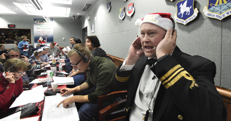 FILE – In this Dec. 24, 2017, file photo, Canadian Lt. Maj. Chris Hache takes a call while volunteering at the NORAD Tracks Santa center at Peterson Air Force Base in Colorado Springs, Colo. Hundreds of volunteers will help answer the phones again when the program resumes on Monday, Dec. 24, 2018, for the 63rd year. Children from around the world call to ask when Santa Claus will get to their house.