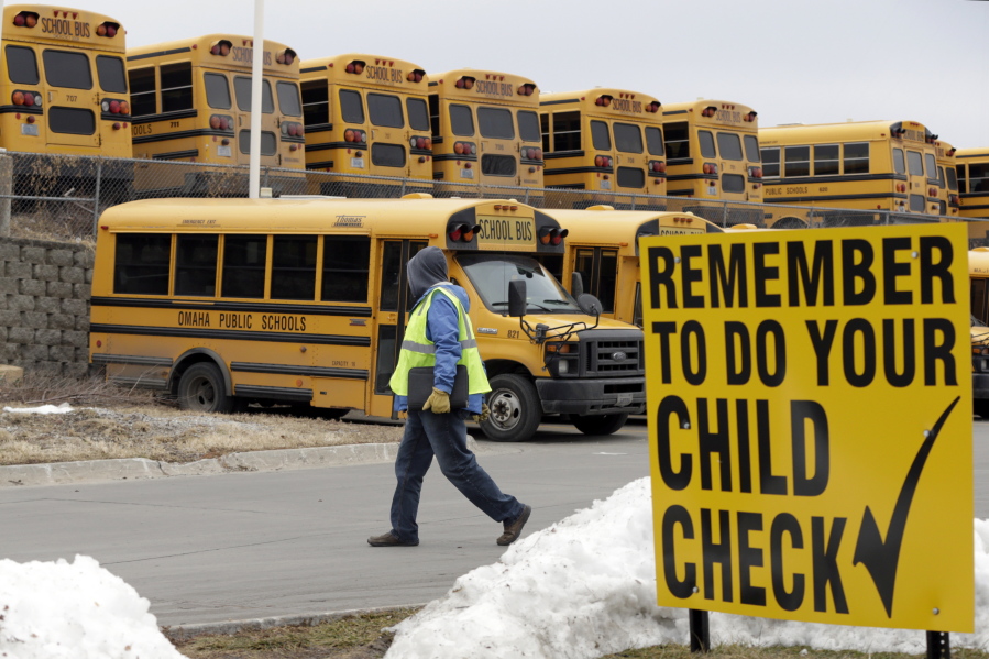 In this Dec. 20, 2018 photo, a driver walks away from the school bus parking lot after his morning shift, in Omaha, Neb. School districts throughout the country are struggling to find school bus drivers, a challenge that has worsened with low unemployment and a strong economy that gives workers a greater choice of jobs.