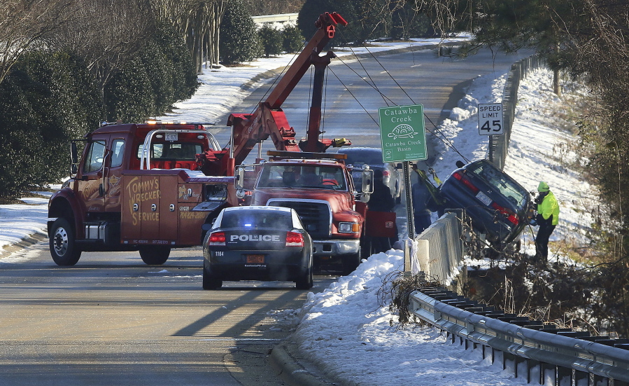 A car is pulled over the barrier after it went down the embankment due to patches of black ice on East Hudson Boulevard on Tuesday in Gastonia, N.C.