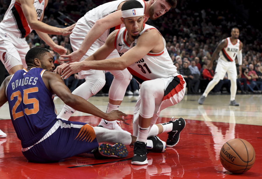 Phoenix Suns forward Mikal Bridges, left, and Portland Trail Blazers guard Seth Curry, right, battle for the ball during the first half of an NBA basketball game in Portland, Ore., Thursday, Dec. 6, 2018.